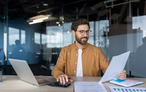 Antreprenor care administrează o microîntreprindere analizând documente fiscale și modificările sistemului de impozitare la laptop