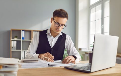 Specialist financiar lucrând cu calculator și documente pentru determinarea statusului de TVA al firmei